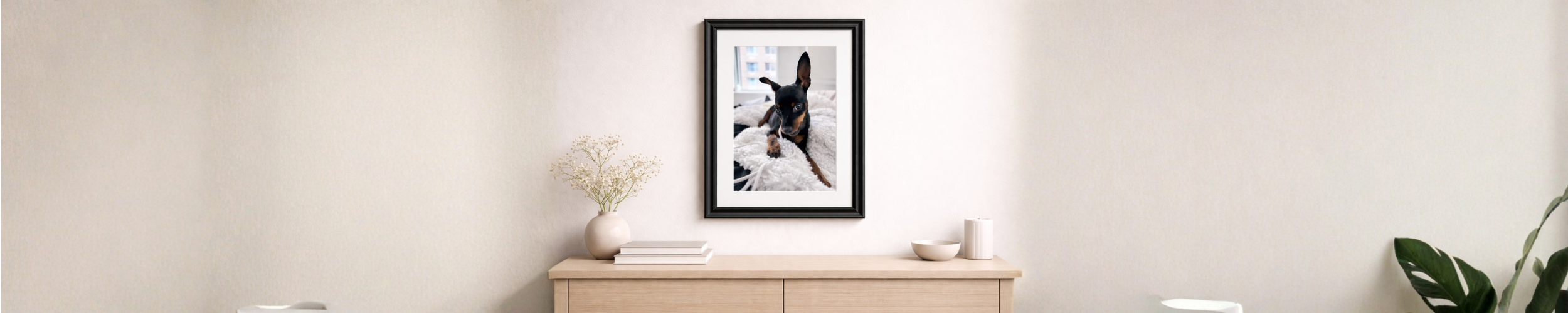 Framed custom dog portrait styled on a neutral wall above a console table